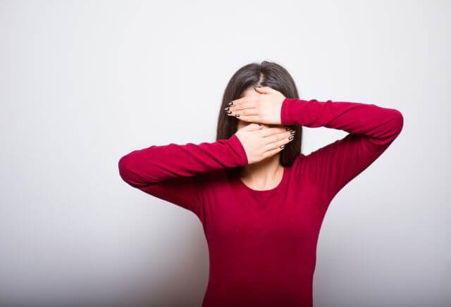 両手で顔を隠す女性