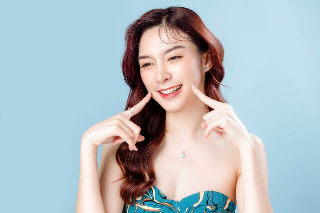 両頬に指をあてて笑う女性